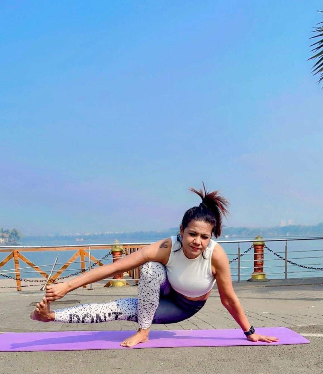 Kanchan performing an advanced yoga pose by the waterfront